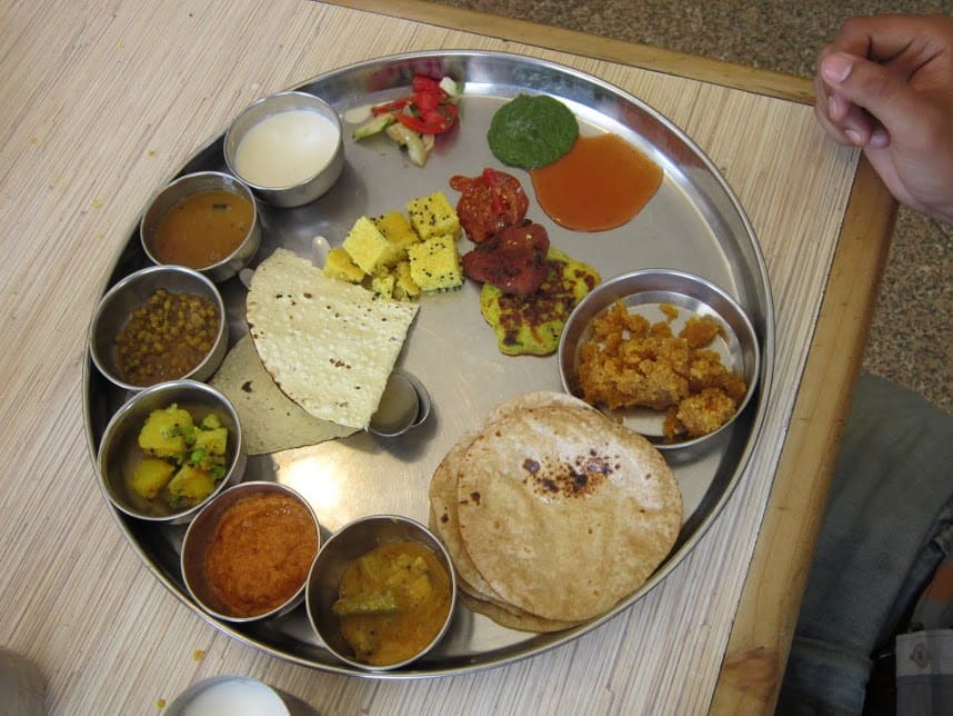 A traditional unlimited Gujarati thali served on brassware.