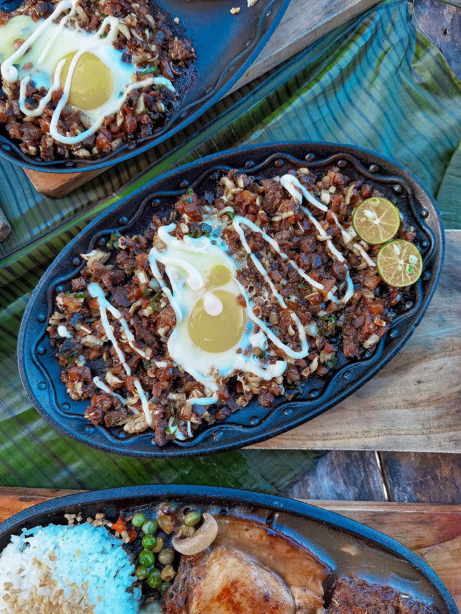 Authentic sizzling sisig served on a hot cast-iron plate with fresh calamansi.