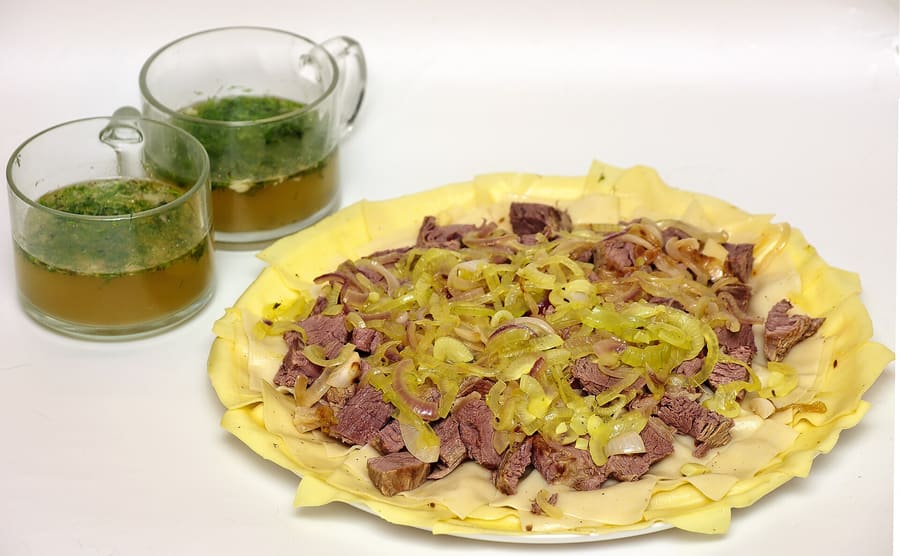 Beshbarmak served hot with boiled meat and thin dough sheets.