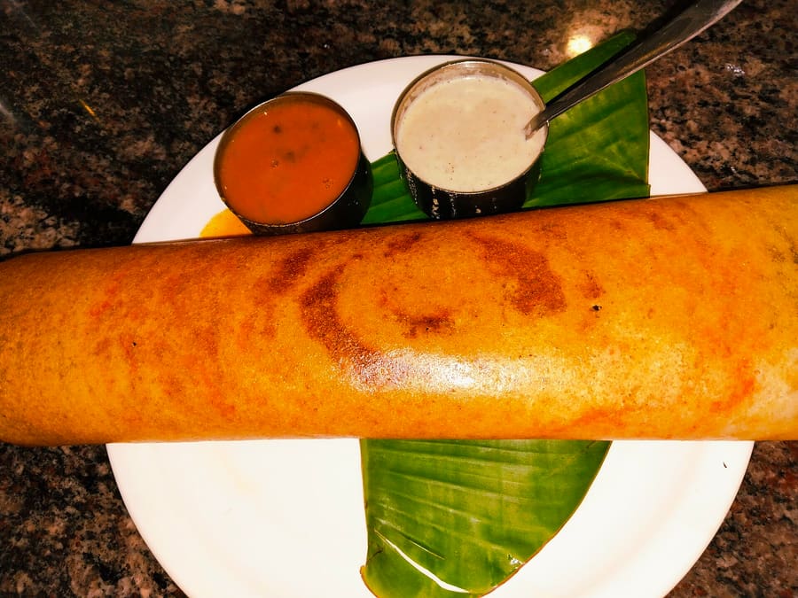 Crisp butter dosa served with coconut chutney and potato palya at a traditional tiffin room.