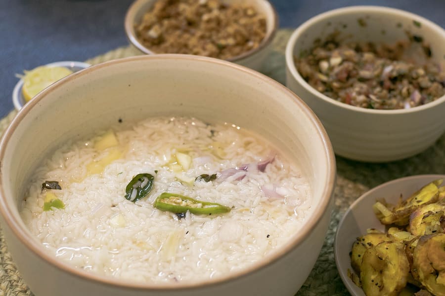 Pakhala bhata served with fried fish, badi chura, and seasonal vegetable sides.