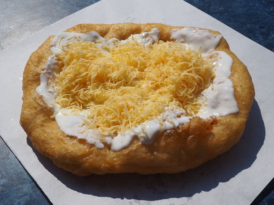 Freshly fried lángos served with sour cream, garlic water, and grated cheese.