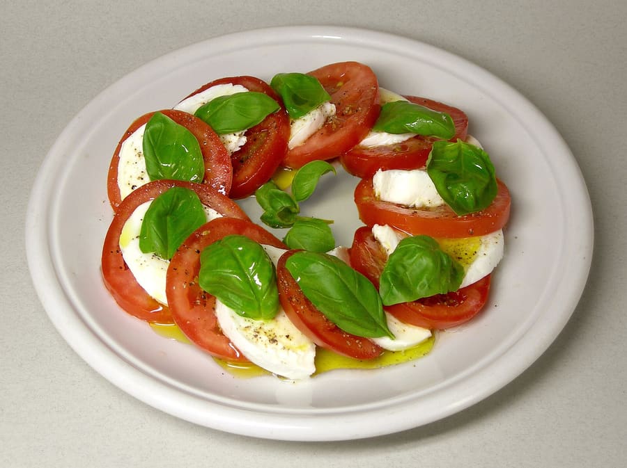 Insalata Caprese served simply with olive oil, fresh cheese, and basil leaves.