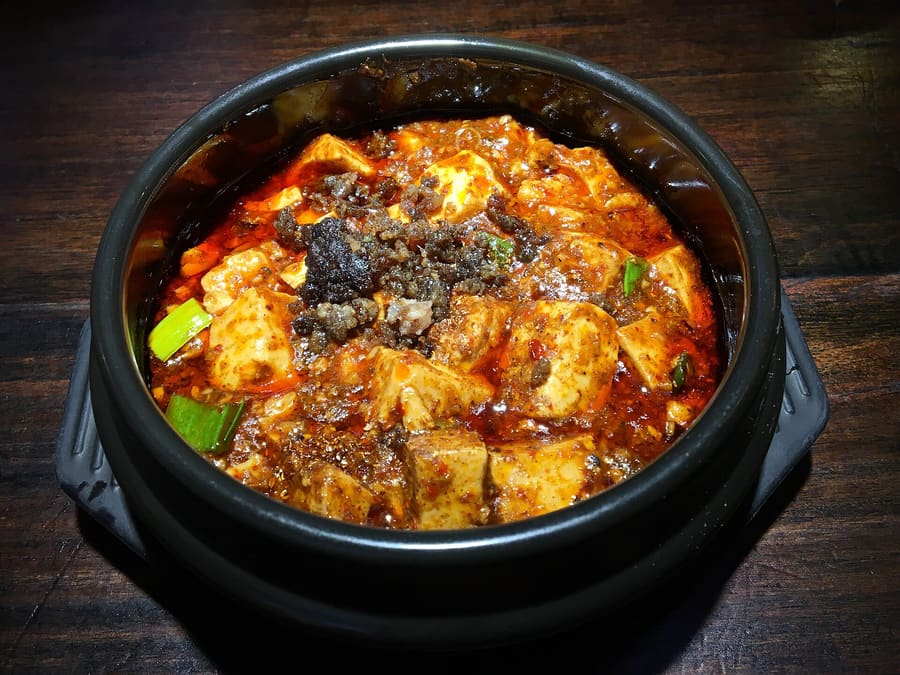 Mapo Tofu served with ground Sichuan pepper and chili oil in a central restaurant.