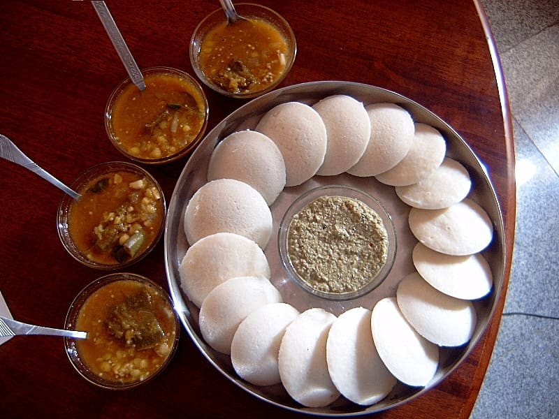 Traditional South Indian tiffin with idlis, vada, and chutneys served on a banana leaf.