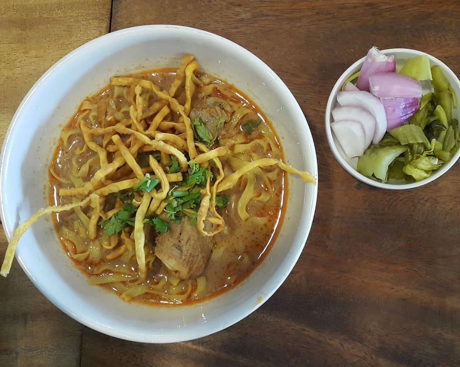 A bowl of Chiang Rai style Khao Soi with tender beef and crisp fried noodles.