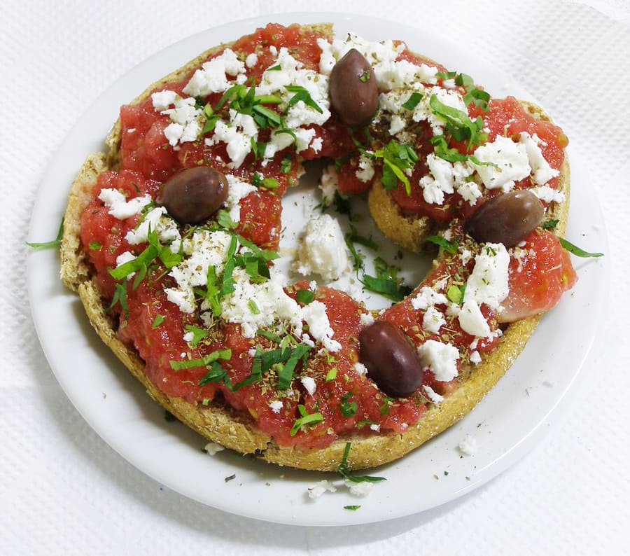 Dakos rusk topped with fresh tomatoes, olive oil, and mizithra cheese.