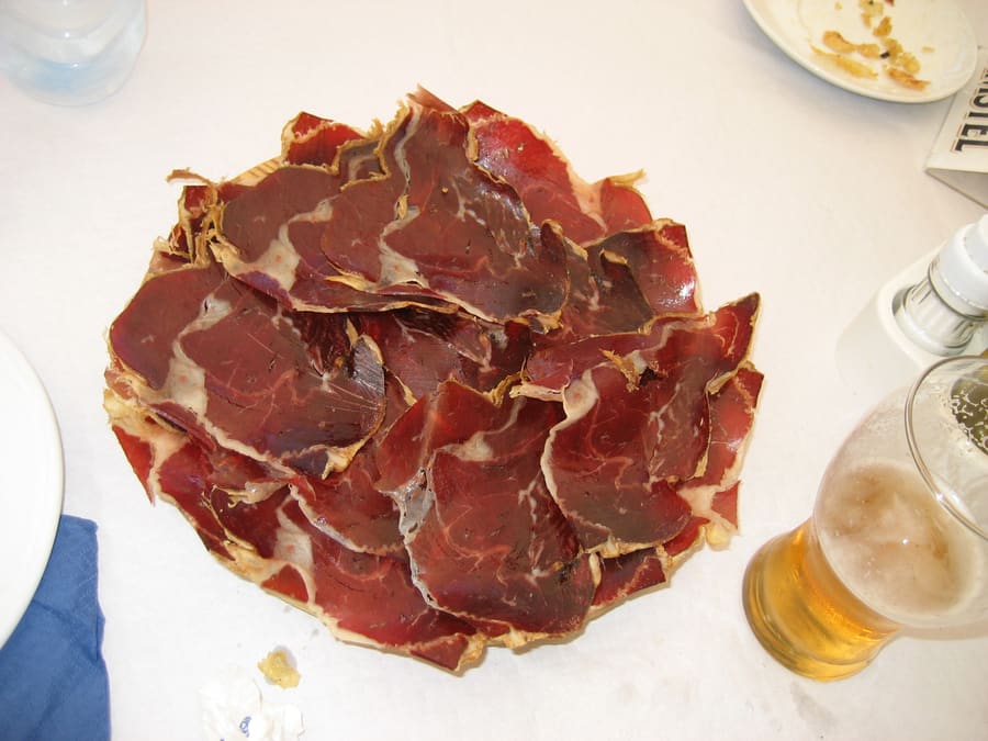 A classic platter of thin-sliced cecina served with avocado, cream, and fresh tortillas.