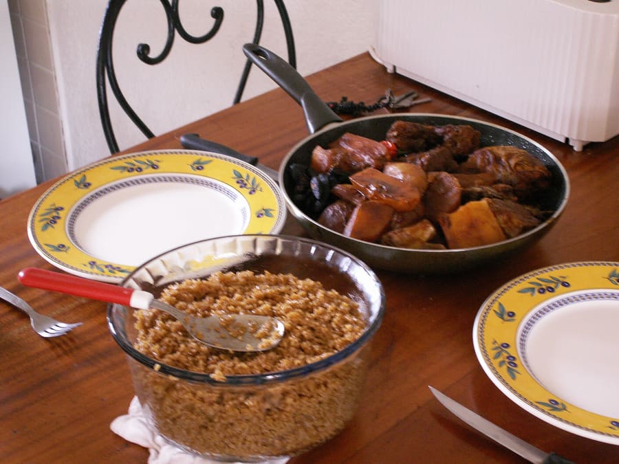 A plate of classic ceebu jën red rice served with fish and root vegetables.