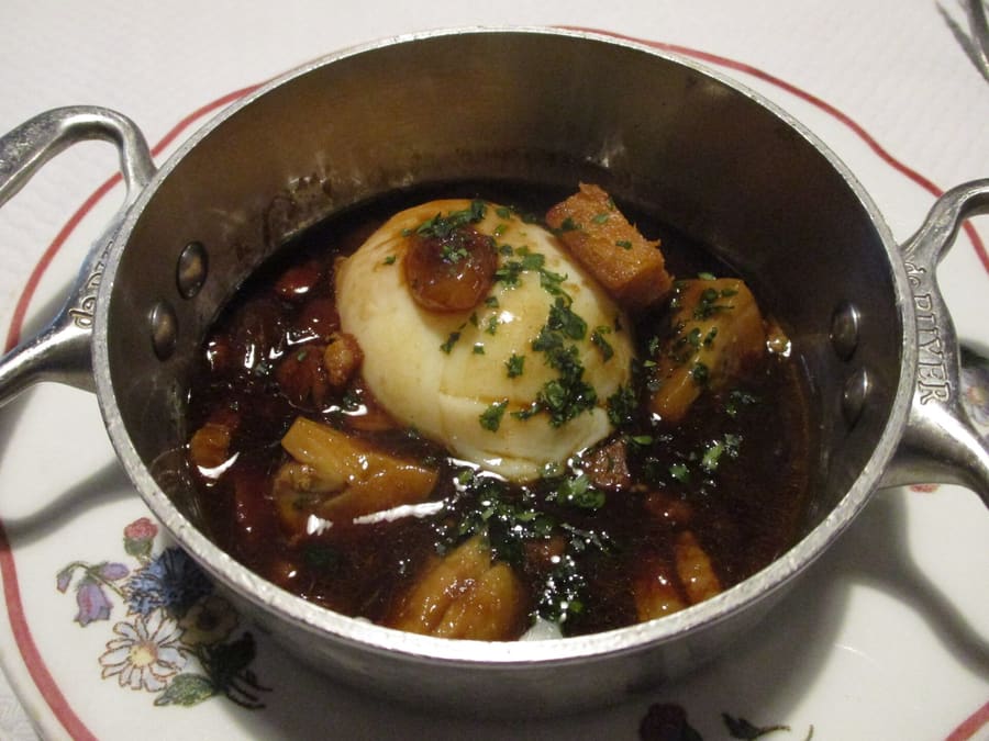 Oeufs en meurette served in a red wine reduction broth at a traditional bistro.