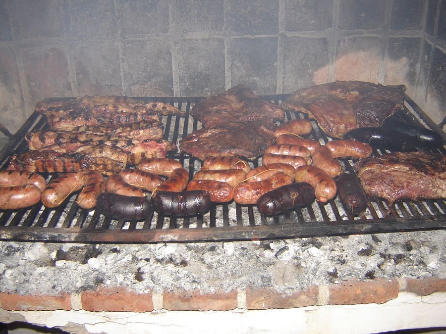 Patagonian lamb roasting slowly over open charcoal fires at a traditional parrilla in El Calafate.