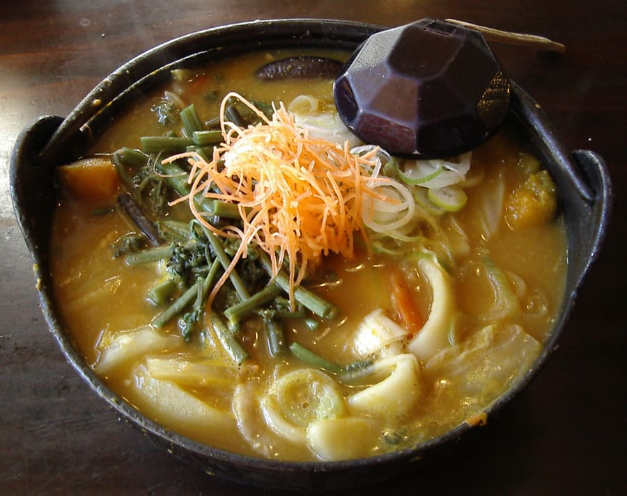 A hot pot of Houtou noodles served in a traditional iron kettle.