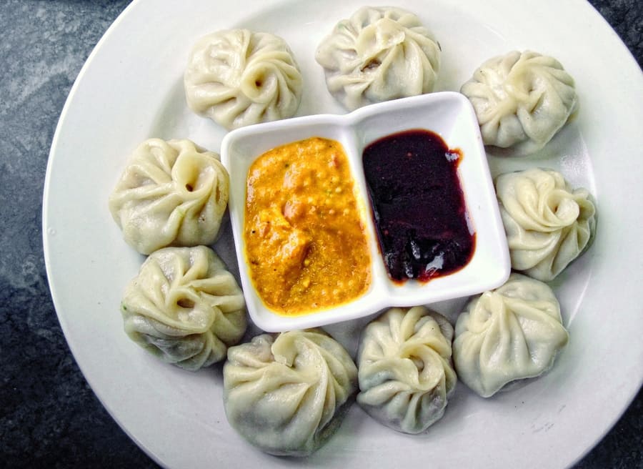 Steamed momos served with fiery fermented red chili chutney.