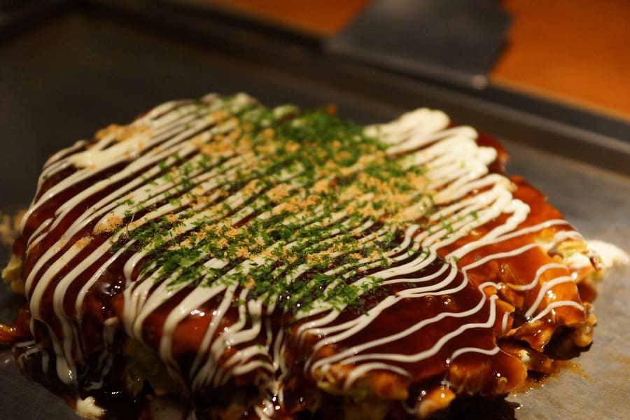 A Hiroshima-style okonomiyaki cooked with cabbage, pork belly, egg, and yakisoba noodles.