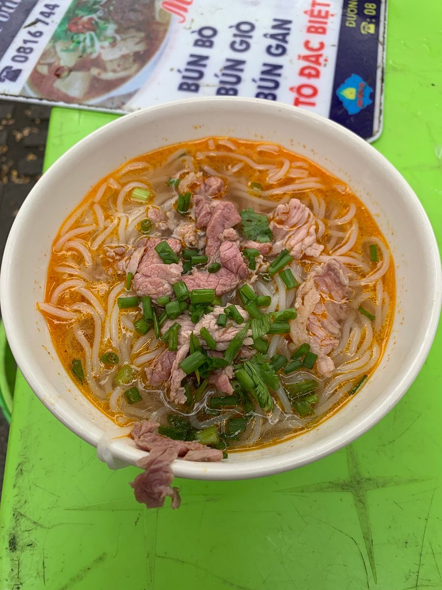 A bowl of bún bò Huế served with fresh herbs and chili paste.