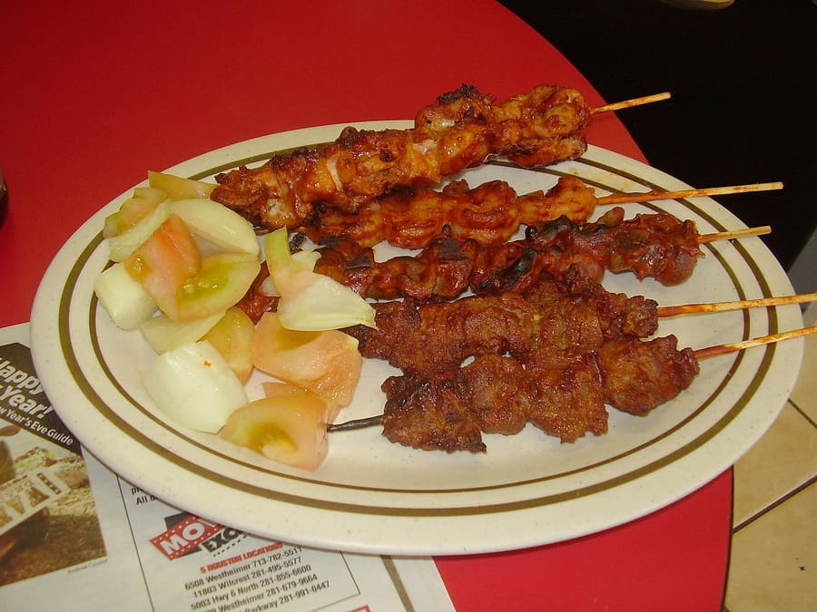 Freshly grilled beef suya served with sliced onions and yaji spice.