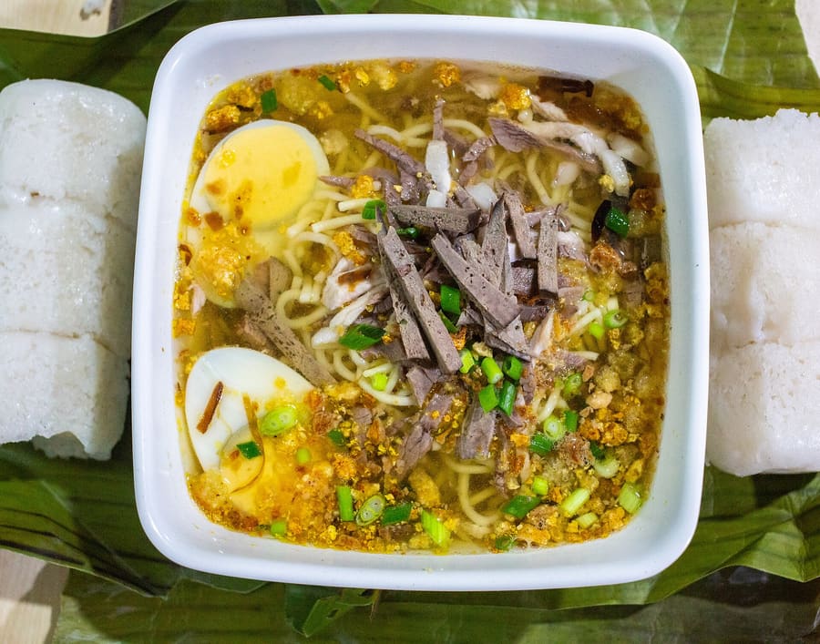 A bowl of authentic La Paz Batchoy topped with crushed chicharon, garlic, and egg.