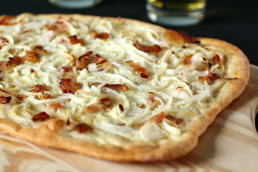 Thin-crust Flammkuchen topped with sour cream, onions, and bacon lardons.