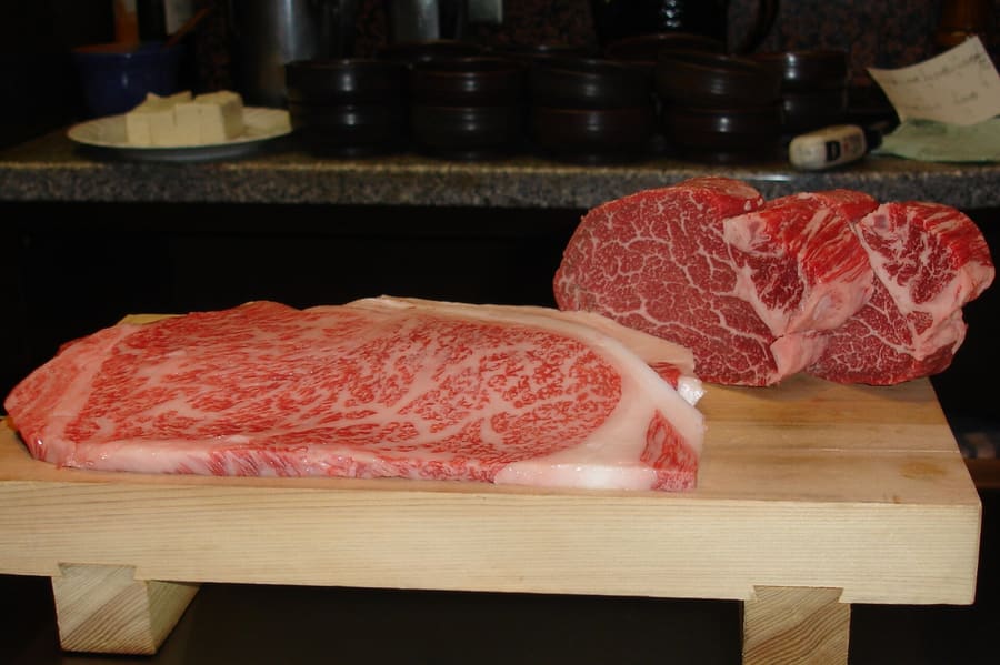 Teppanyaki chef preparing certified Kobe beef over high heat.