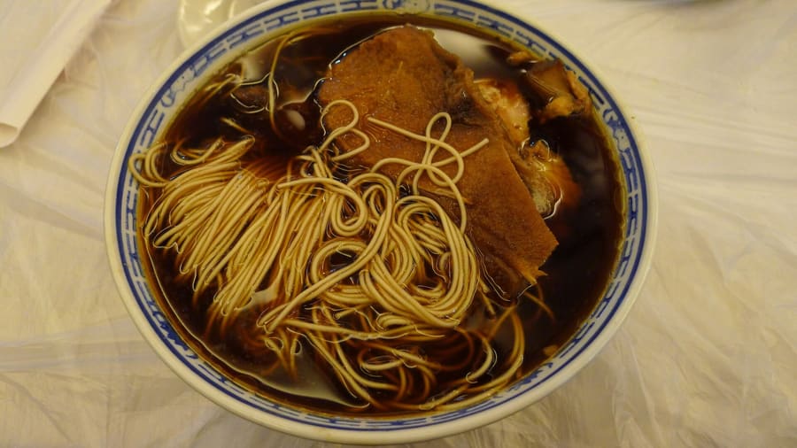 A steaming bowl of traditional Ao Zao red-oil duck noodles.