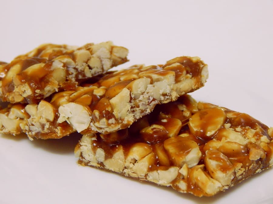 Fresh groundnut chikki cooling on marble trays at a local workshop.