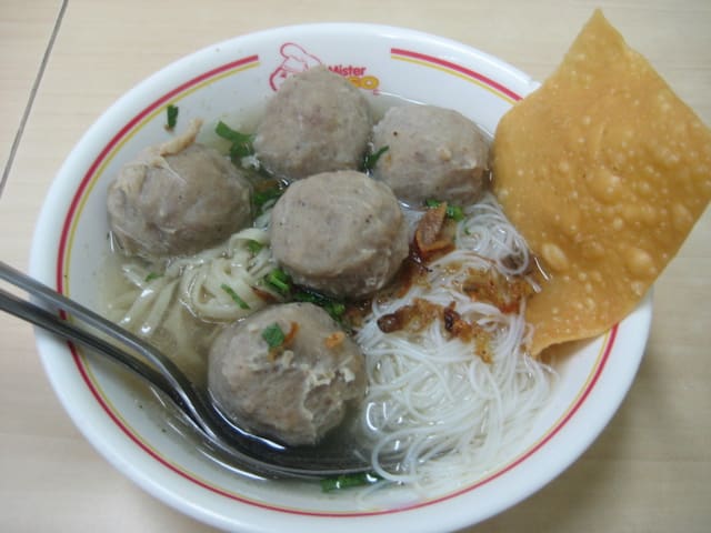 A bowl of Bakso Malang served with fried wontons and steamed tofu.