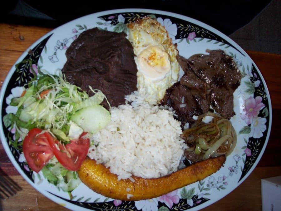 A traditional casado plate served with black beans, rice, and fresh plantains at Soda La Amistad.