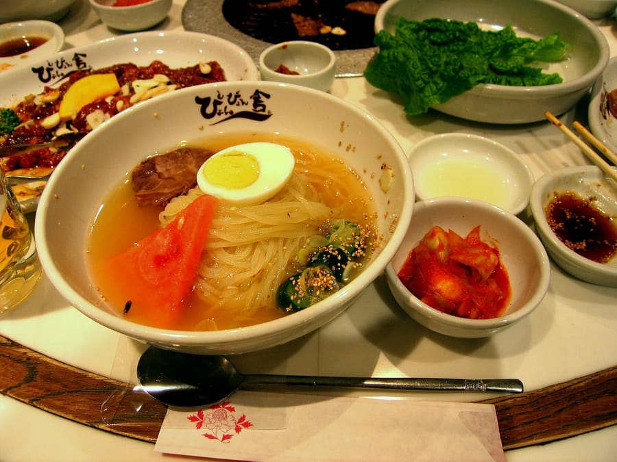 Morioka Reimen features cold translucent starch noodles topped with kimchi and seasonal fruit.