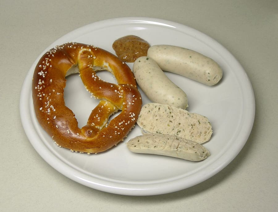 Weißwurst served in warm water with sweet mustard and a fresh pretzel.