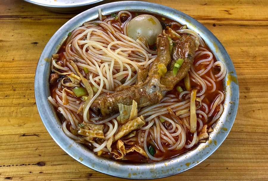 A hot bowl of Guangxi rice noodles with pickled bamboo shoots and chili oil.