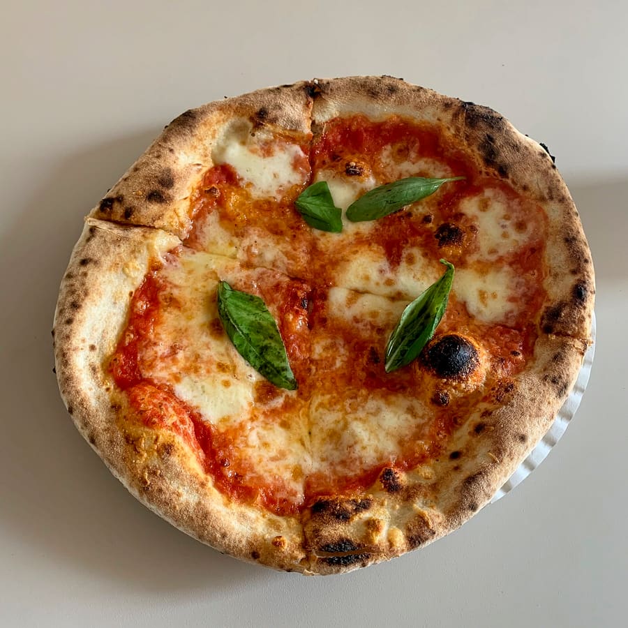 A classic Neapolitan Margherita pizza baked in a wood-fired domed oven.