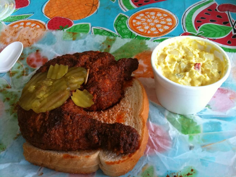 Nashville hot chicken, served over white bread with pickle slices.