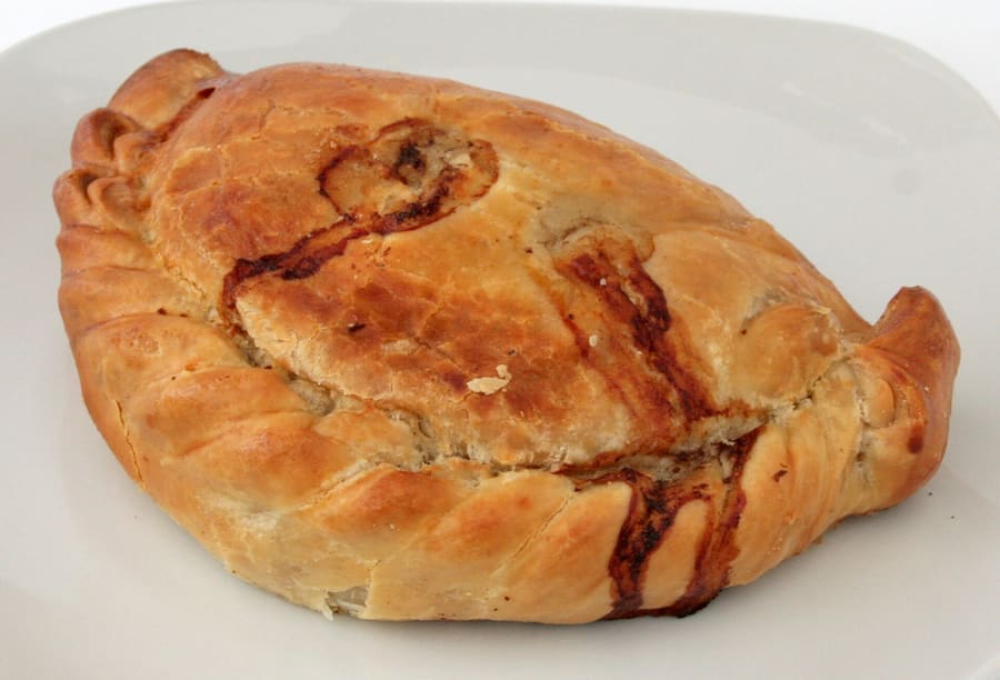 A traditional baked Cornish pasty, crimped along the side edge.