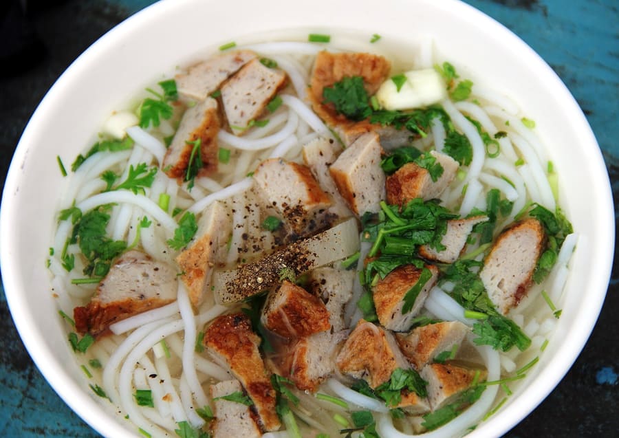 Bún chả cá served with fried fish cakes and fresh herbs.