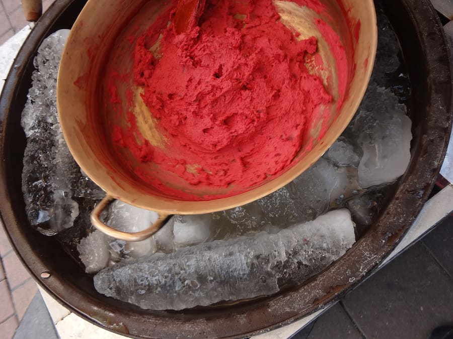 Helado de paila churned by hand in a copper bowl resting on salted ice.