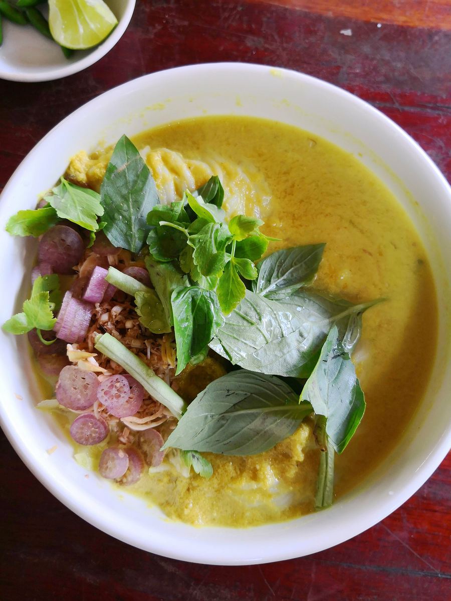 Fresh nom banh chok noodles topped with coconut fish curry and sliced cucumber.