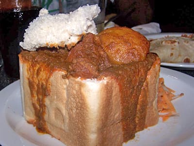 A classic mutton bunny chow served with carrot salad.