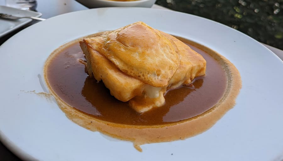Francesinha served hot with a fried egg and fries in Porto.
