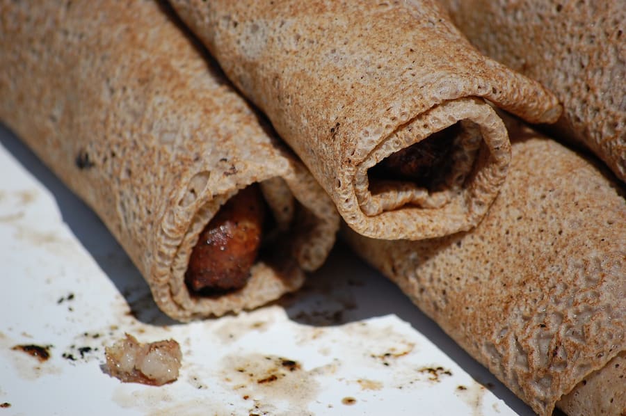 A traditional galette-saucisse sold hot at a Saturday market stall.