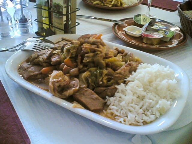 Feijoada served with farofa, kale, and orange slices at a traditional Rio restaurant.