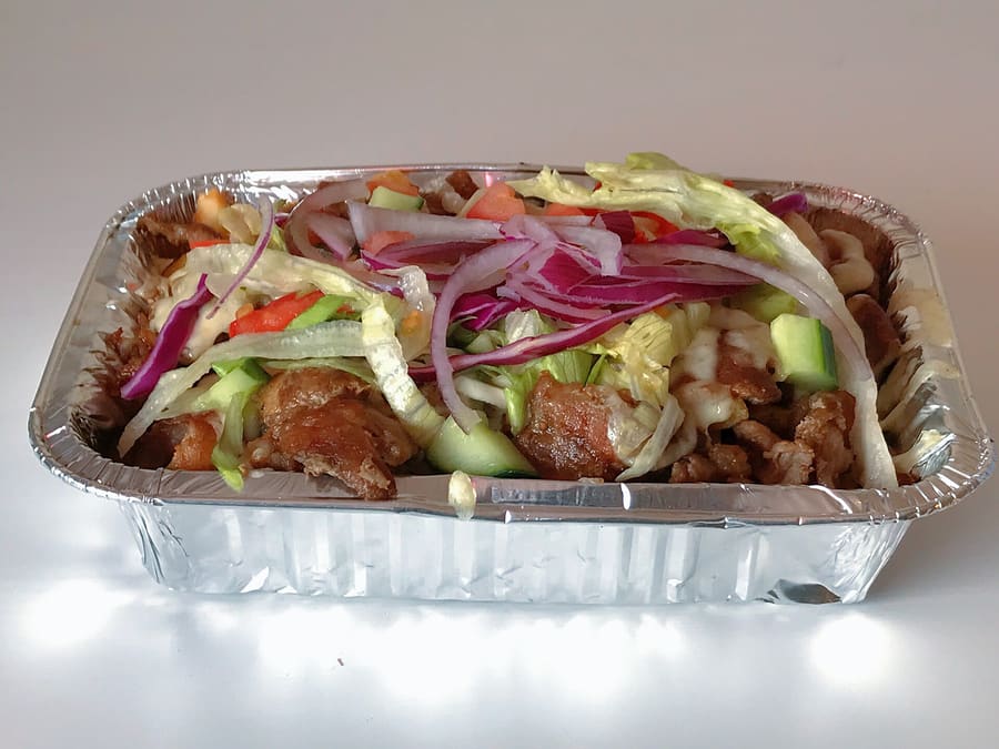 A layer of fries topped with shawarma, melted Gouda, and salad, created in Rotterdam.