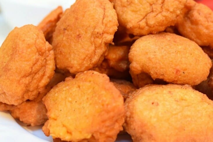 Acarajé served fresh from a street kiosk, filled with vatapá paste and dried shrimp.