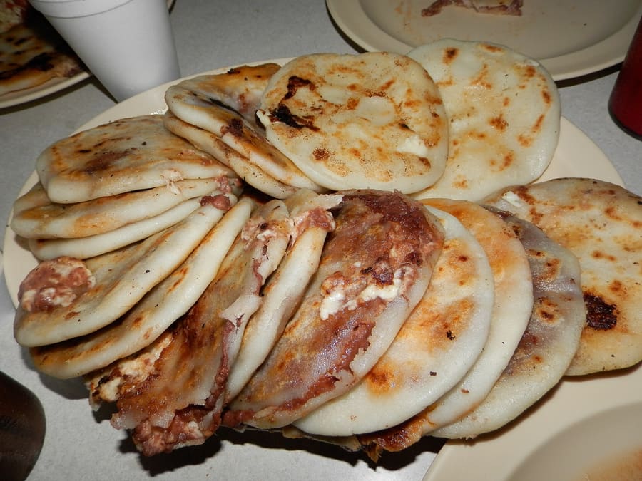 Pupusas cooking on a hot metal griddle at a neighbourhood pupusería.