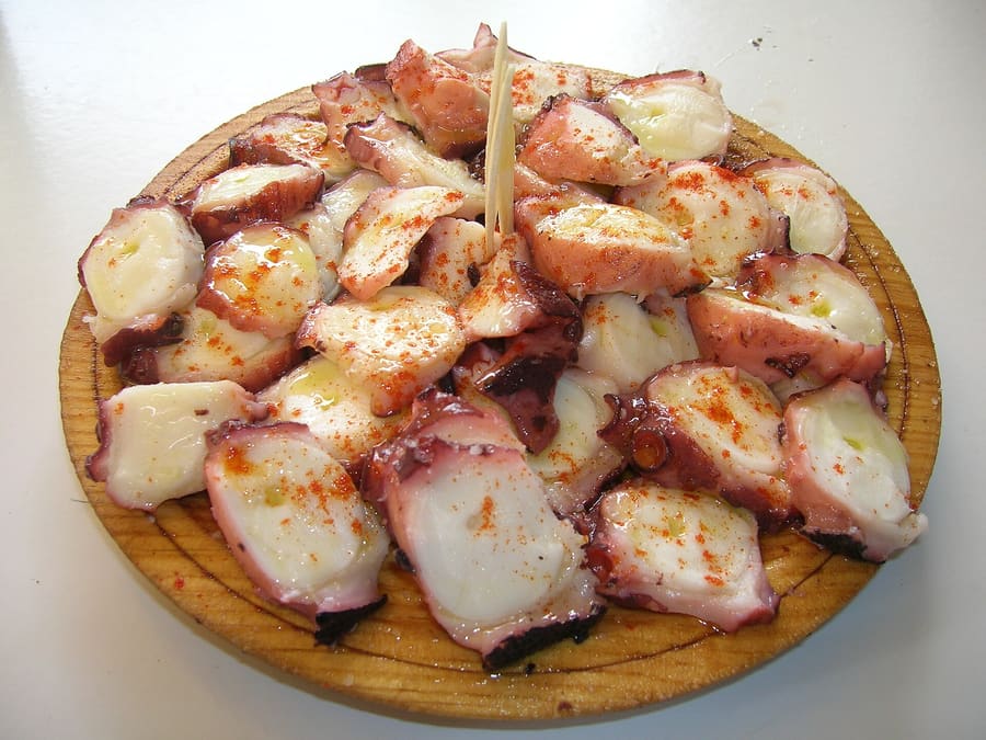 Polbo á feira served on a traditional round wooden platter with paprika, coarse salt, and olive oil.