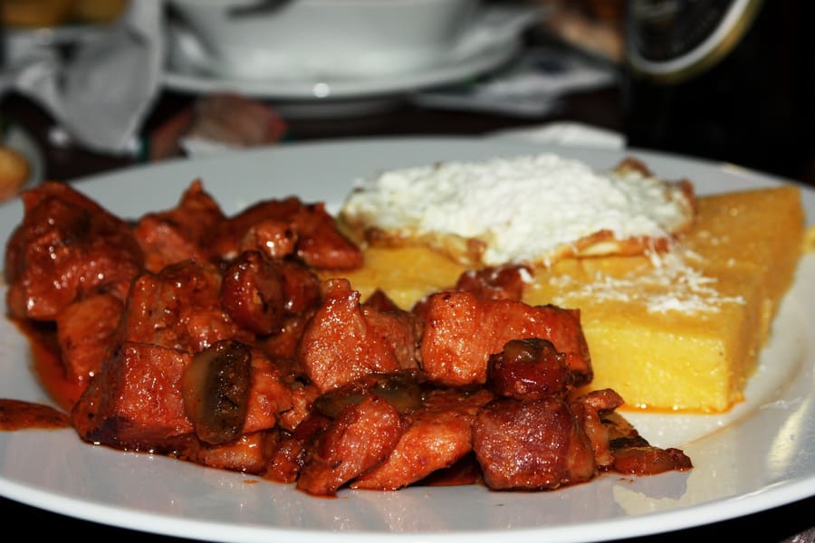 Tochitură munteană served with polenta, telemea cheese, and a fried egg.