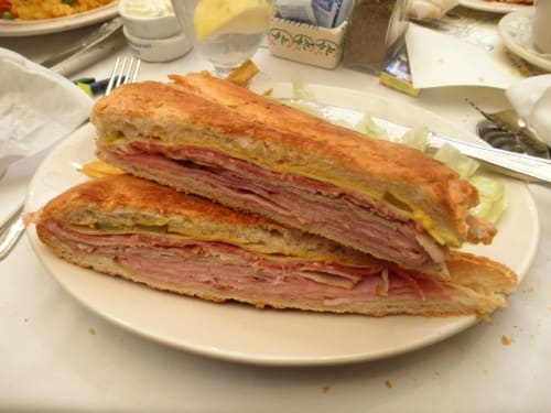 A classic pressed Cuban sandwich with ham, roast pork, Swiss cheese, pickles, mustard, and salami.