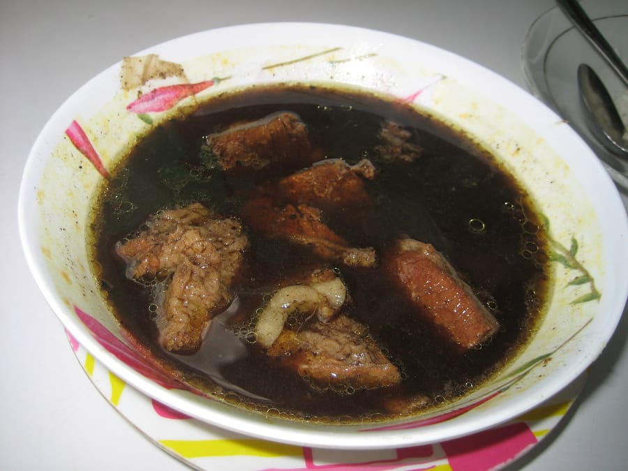 A bowl of traditional Rawon beef soup, colored dark black by fermented keluak nuts.