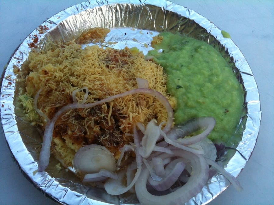 A hot plate of fresh Surati Locho topped with butter, crisp sev, and green coriander chutney.