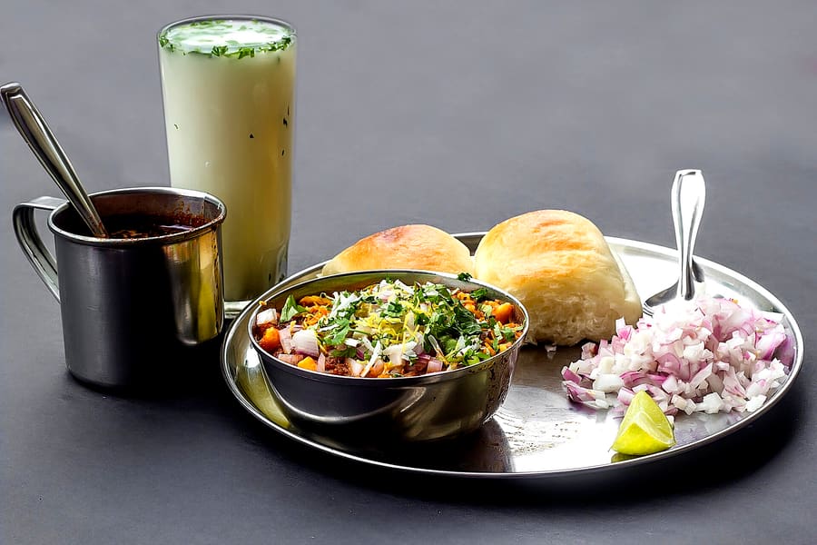 A plate of spicy Mamledar Misal topped with farsan and chopped onions.