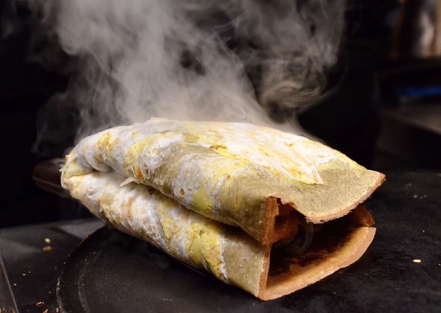 A fresh jianbing guozi prepared on a heated iron skillet.